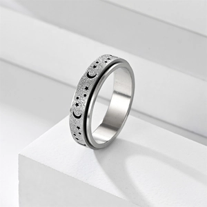 Macro view of rotating star and moon anxiety ring with a frosted silver finish