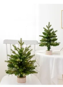 Mini PE Christmas trees with warm LED lights and natural wooden bases on a white chair