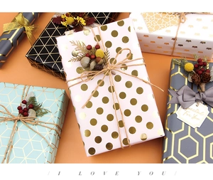 Dettaglio di carta regalo di lusso con motivi geometrici dorati, nastri e cartellini