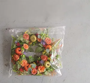 Detail view of autumn wreath with orange roses and pumpkins in plastic packaging