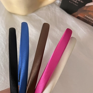 Close-up of five satin padded headbands in black, blue, brown, rose, and cream colors