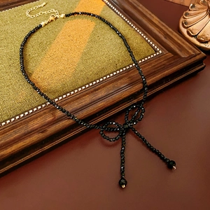 Detail of a vintage black beaded necklace featuring a bow design and lobster clasp