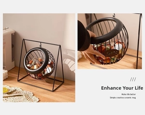 Detail view of a black metal coffee pod holder with hanging frame and wire storage basket