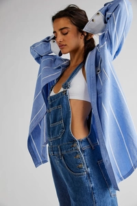 Detail of layered blue denim overalls with a striped shirt and white sports top