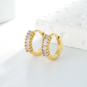 Vue macro de boucles d'oreilles créoles dorées avec zircons violets sertis en rail