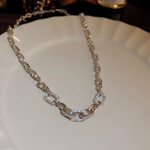 Close-up of silver geometric link chain with sparkling zircon inlay on white plate