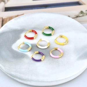 Set of seven colorful enamel hoop earrings in gold finish on marble display