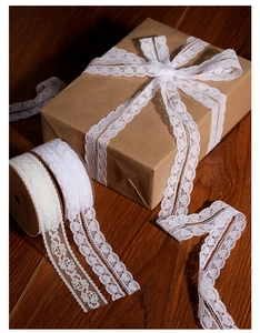 Detailed view of white floral lace ribbon roll for gift wrapping on wooden background