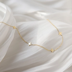 Minimalist gold four-leaf clover pendant necklace on elegant white silk background