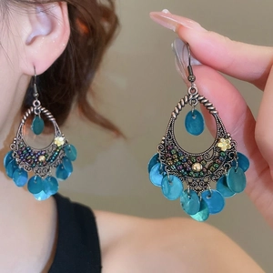 Détail de boucles d'oreilles fleur vintage avec pompons bleus et design rétro