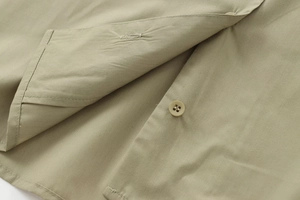 Close-up of olive green poplin shirt showing detailed stitching and four-hole buttons