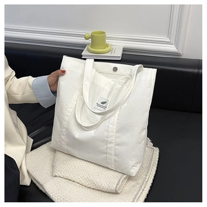 Detail of white canvas tote bag with magnetic metal snap closure and interior tag