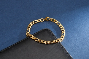 Macro shot of golden Figaro link chain bracelet on a black leather display stand