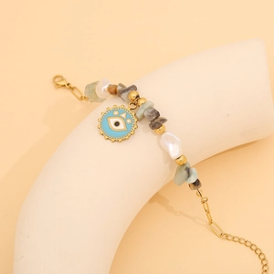 Detail of natural stone beaded bracelet with blue evil eye pendant and baroque pearls