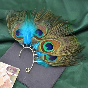 Close-up of golden peacock feather ear wrap on dark silk background for women