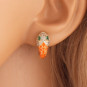 Detailed close-up of a snake earring with orange enamel, green and clear zircon stones