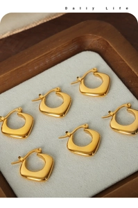 Makro-Detail von drei Paar quadratischen goldenen Creolen auf einem Samt-Display-Tablett
