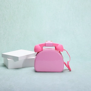 Detailed view of pink telephone-shaped handbag with glossy finish and retro handset handle