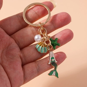 Detail shot of ocean theme keychain with green enamel mermaid, shell and star charms