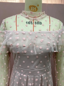 Detail of pink polka dot mesh dress featuring long sleeves and ruffled off-shoulder neckline