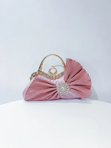 Detail view of pink pleated satin evening bag with sparkling rhinestone flower and gold handle