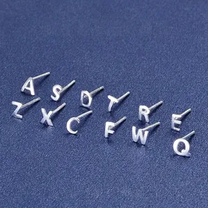 Minimalist S999 sterling silver letter stud earrings in a variety of alphabets on blue base