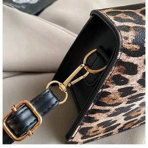 Macro view of gold hardware hooks and leopard print texture on a retro crossbody bag