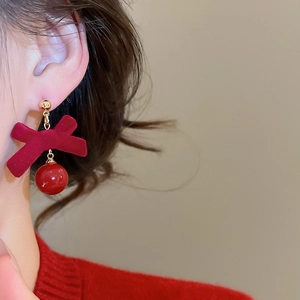 Détail de boucles d'oreilles nœud rouge floqué avec perle brillante sur modèle
