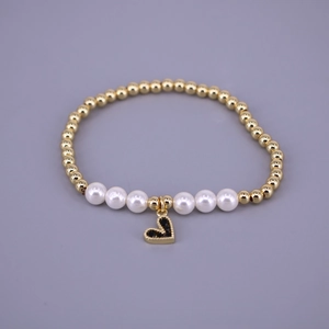 Detailed view of beaded bracelet featuring gold metal beads with white pearls and heart charm