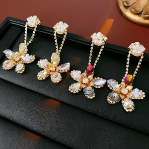 Detailed close-up of gold flower earrings with pearls and crystals on black leather