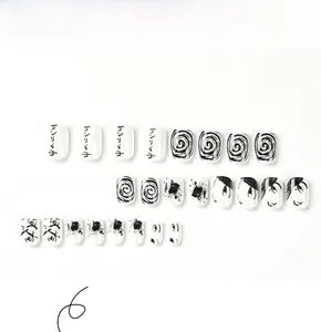 Detail of 24 black and white press-on nails with Japanese anime art and gothic patterns