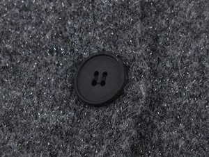 Detailed macro shot of dark grey knit cardigan fabric with metallic yarn and matte button
