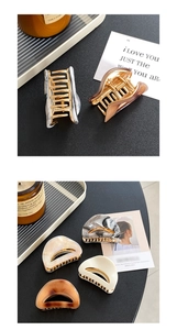 Close-up of semi-round acetate shark hair clips with golden metal teeth on a dark surface