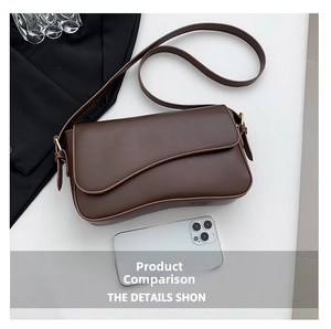 Detail view of brown leather crossbody bag with curved flap and gold metal buckle