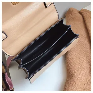 Detail view of the beige crossbody bag showing two main interior compartments and woven strap