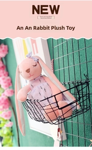 Detailed view of a pink plush rabbit doll wearing a floral purple dress in a wall basket