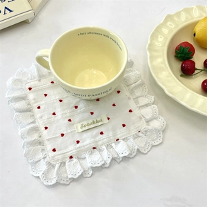 Square cotton coaster with white lace and red hearts featuring a ceramic mug on a table