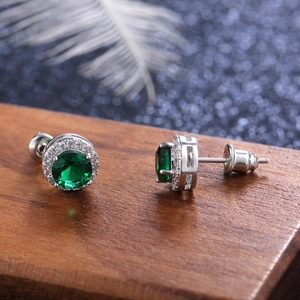 Macro shot of silver round halo stud earrings with green emerald-cut zircon and tiny diamonds