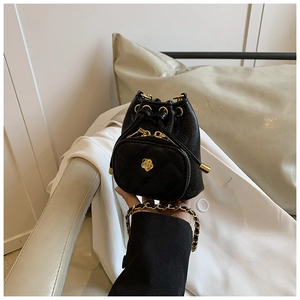 Detail of mini black bucket bag with camellia ornament and gold chain strap