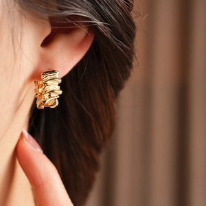 Detail of irregular golden textured hoop earrings with a crumpled metallic finish