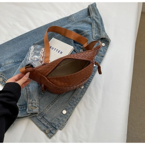 Brown woven texture crossbody bag with adjustable strap shown in a lifestyle setting