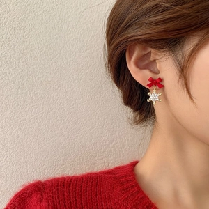 Close-up of a model wearing a festive red bow and sparkling zircon snowflake drop earring