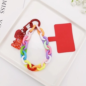 Colorful plastic link phone wrist strap with bear charm and heart pendant on white tray