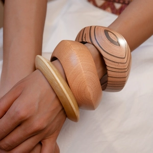 Close-up of three stacked wooden bangles in different widths and natural grain patterns
