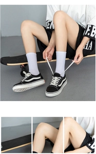Detail view of black canvas low-top sneakers featuring classic white side stripes