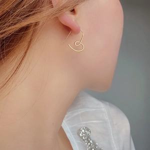 Close-up of gold heart-shaped earrings with twisted texture worn by a model