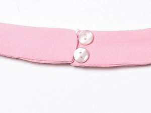 Detail of pink halter neck dress featuring two white pearlescent buttons on fabric