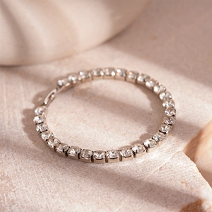 Detailed view of silver tennis bracelet with round cubic zirconia on stone surface
