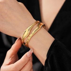 Detailed view of irregular wavy gold-plated cuff bracelet with hammered metal texture