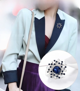 Detail of geometric silver brooch with blue sapphire gemstone on a blazer lapel